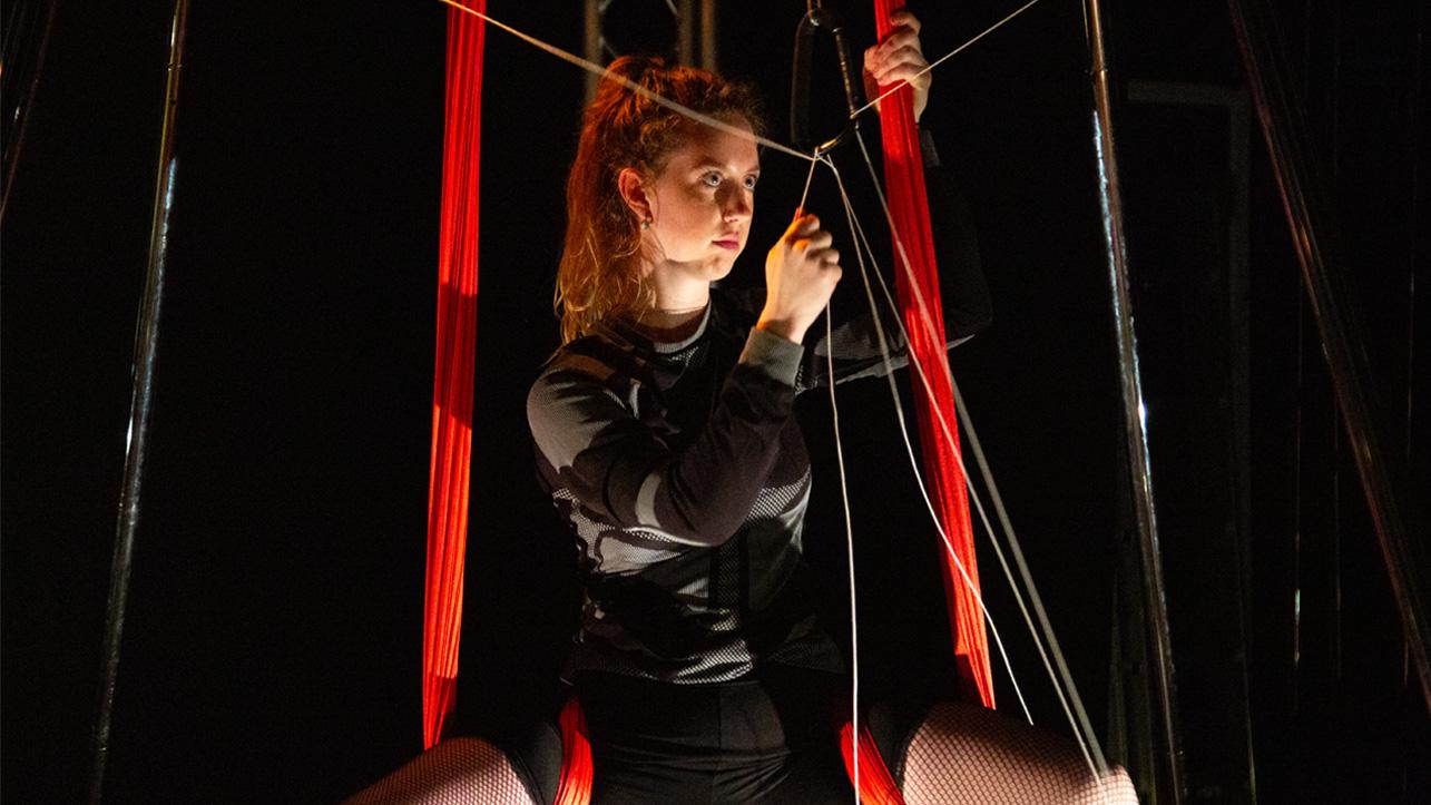 A woman is suspended on ribbon trapeze equipment