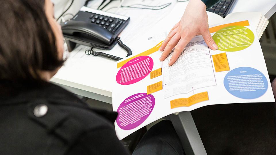 A staff member showing a leaflet to a student