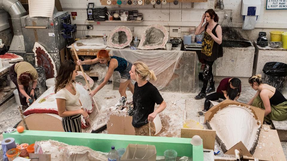 Seven students working in the casting art practice area, surrounded by casting equipment and materials