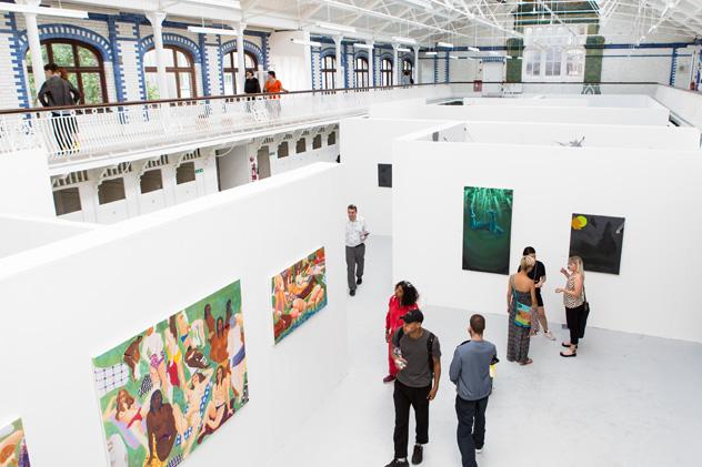 Degree show visitors walking around an art exhibition looking at paintings