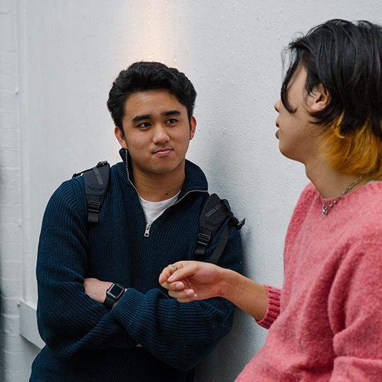 Two students talking in a university corridor.