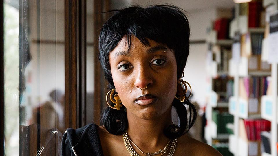 A portrait of Heavadny, a young Black woman, in the Goldsmiths library