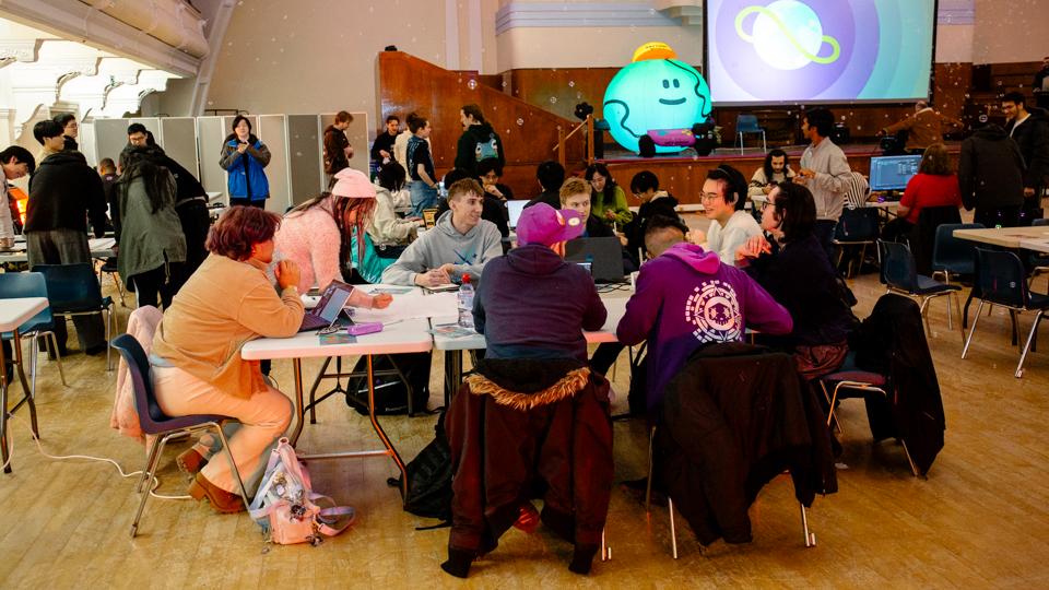A group of people gathered around a table to take part in the Global Game Jam, with bubbles floating in the air above.