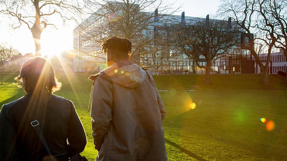 A student and parent walking around campus towards the sun.