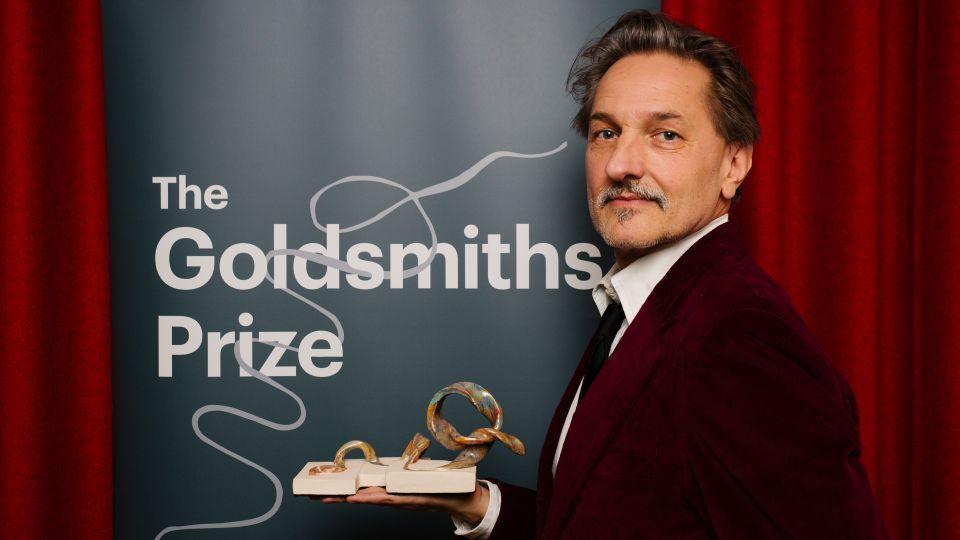 C.D. Rose in a red velvet jacket holding the ceramic trophy 