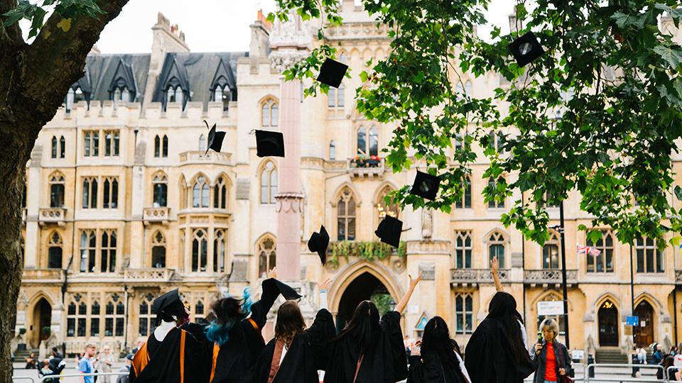 A group of university graduates throwing their graduation caps in the air.
