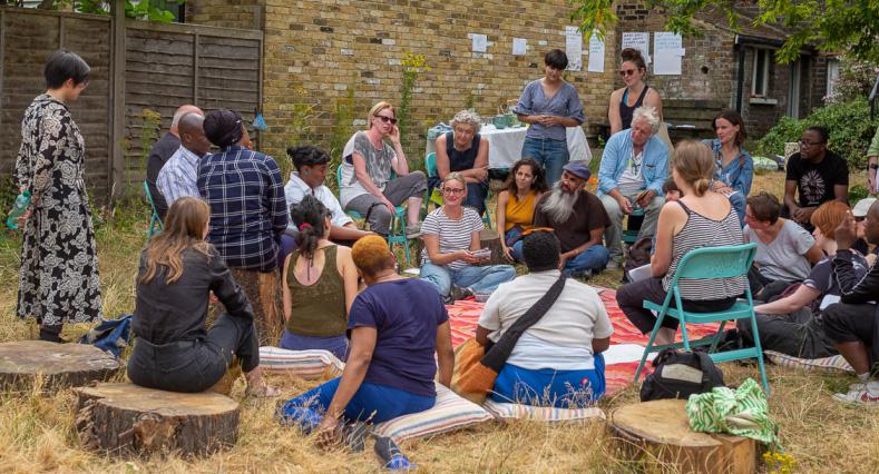 Over 20 people sitting down in the garden discussing the project