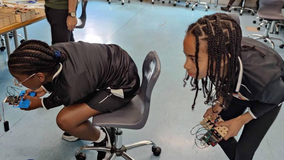 Two year 7 operate robots seated on wheely chairs
