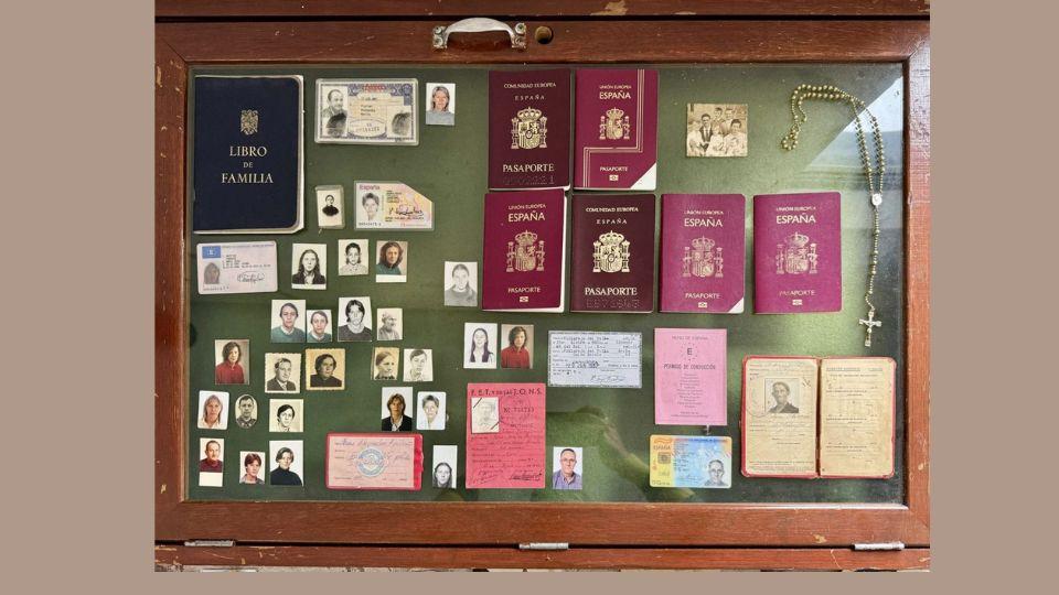 Photo of display case containing old passports, family portraits and rosary 