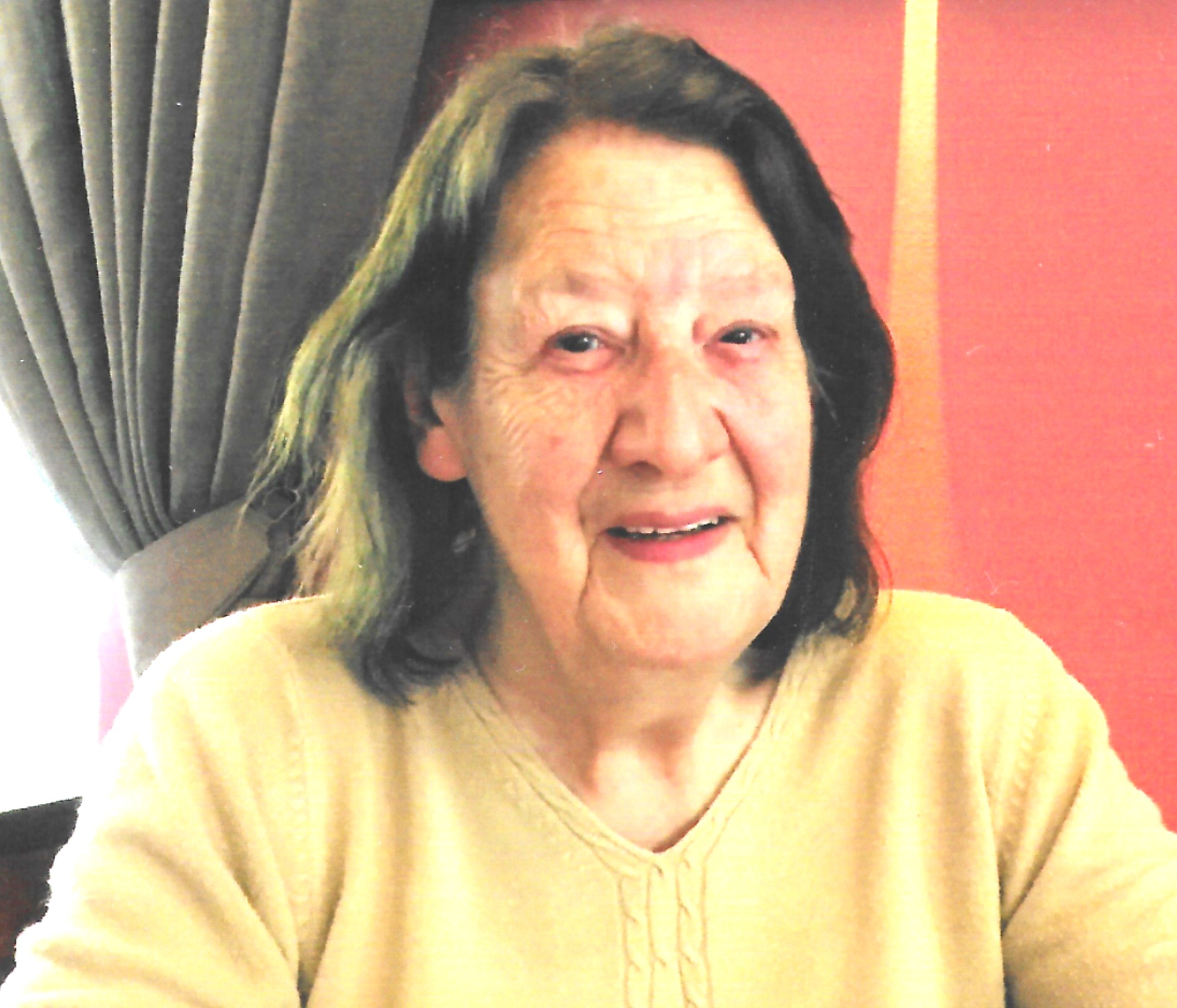A scanned photo of a woman with brown hair, she is smiling at the camera