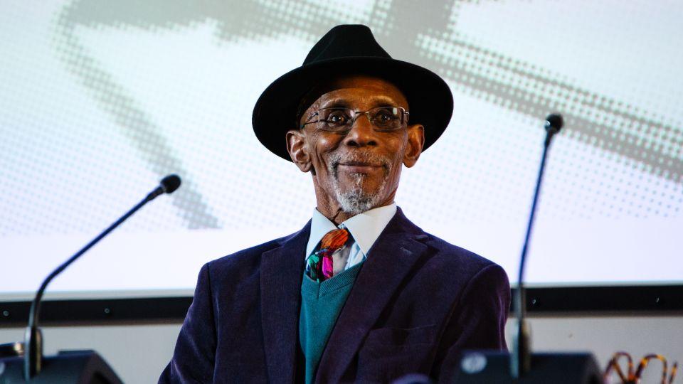 Picture of a smiling Linton Kwesi Johnson on the panel. 