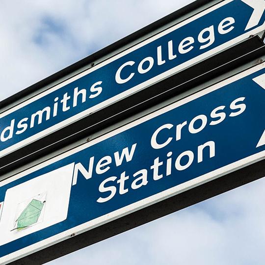 Closeup of a sign for New Cross station.