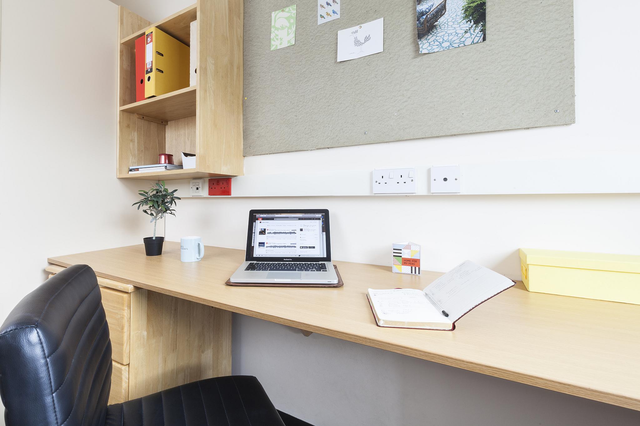 A desk with a laptop in a student room