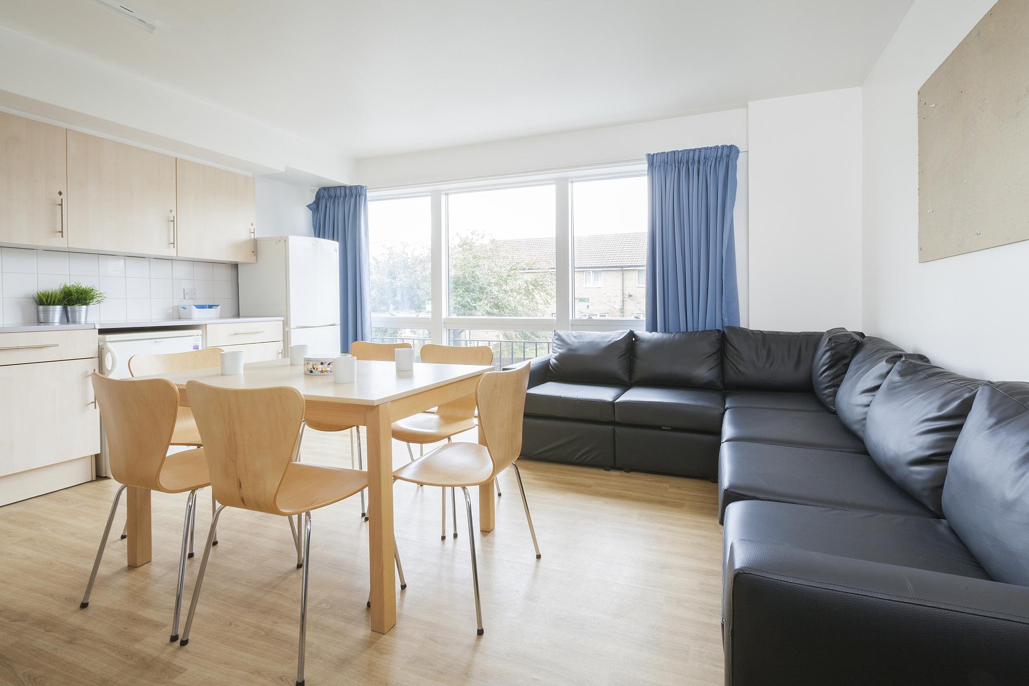 A kitchen space with a table and large leather corner sofa