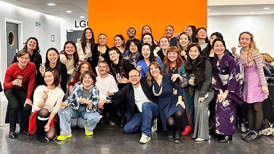 Around 30 smiling students and academics group together to pose for a happy celebration picture