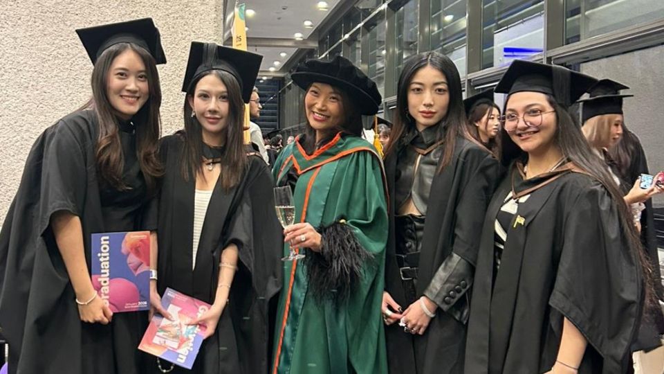 Four Imagine Challenge participants in graduation gowns pose with their tutor