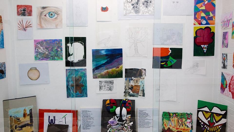 Various art pieces and drawings on a white wall.