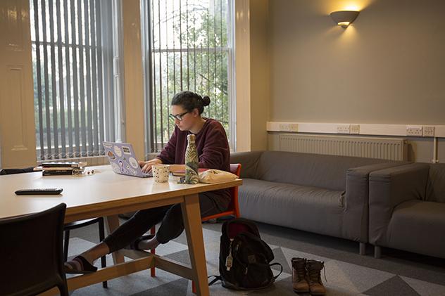 A female student sitting in a social space in halls