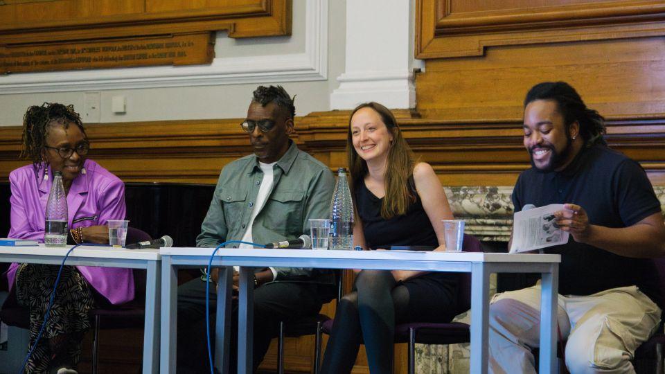 The panellists seated at a table with wooden panels behind them 