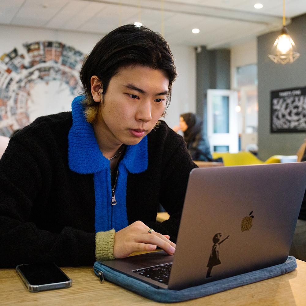 A student looking at a laptop with concentration.