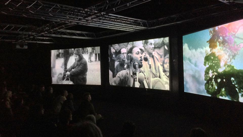 Students watching a film across three large-format screens in the Sonics Immersive Media Lab.