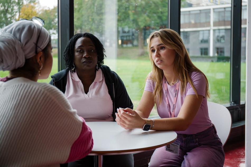 Three students sit at a cafe table having a conversation