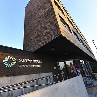 Outside of a brick building with a white conservatory and grassy area.