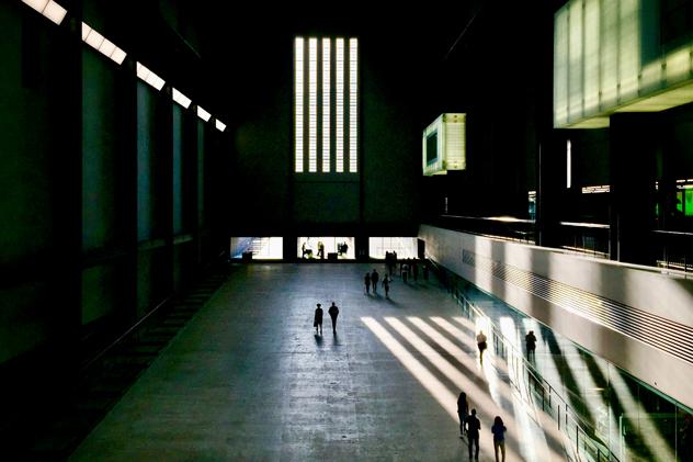 The Turbine Hall at Tate Modern &ndash; a huge space with a slope that has people walking up it, and shadows cast from windows on the side of the building