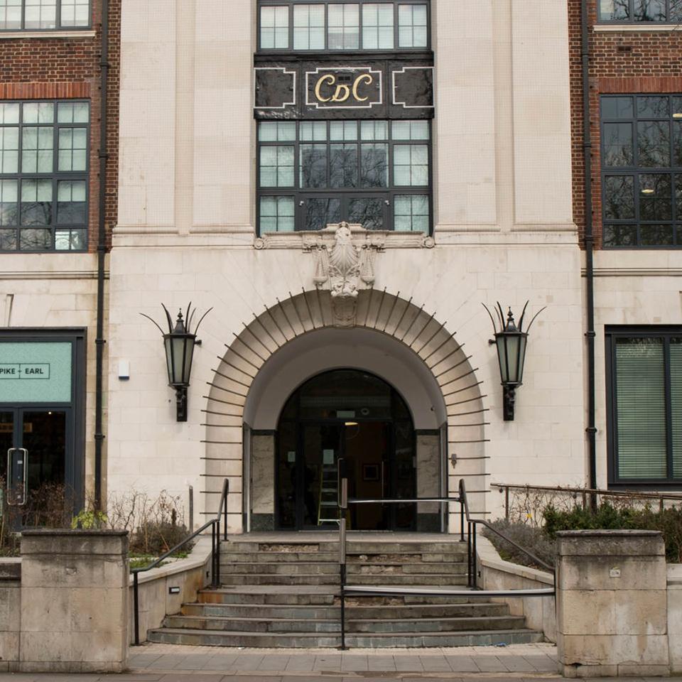 Outside of a building with an arched doorway and staircase leading up.