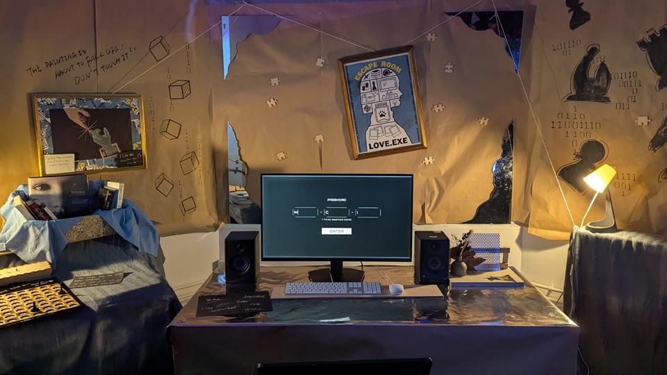 A desk with a computer monitor surrounded by decorations and clues