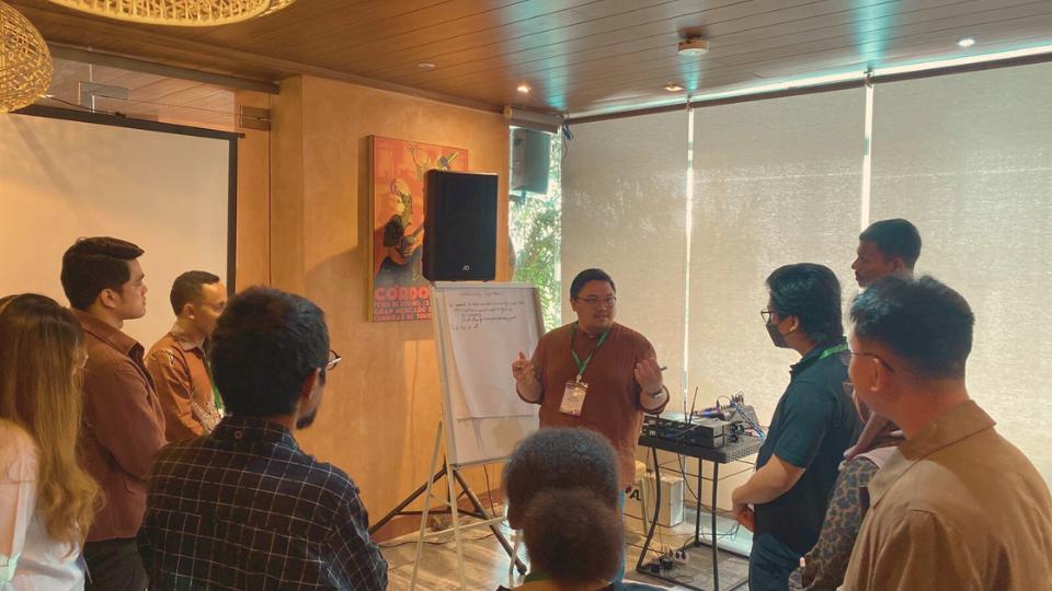 Group of young people stand in circle whilst facilitator presents